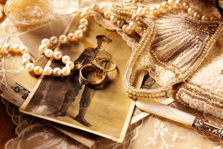 Collection of sentimental antique items: old black and white photograph, pearl necklace, lace, gold rings, beaded purse