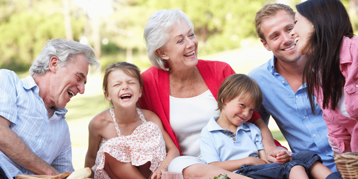 grandparents, parents, and kids having a picnic laughing together