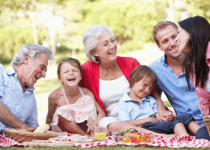 grandparents, parents, and kids having a picnic laughing together