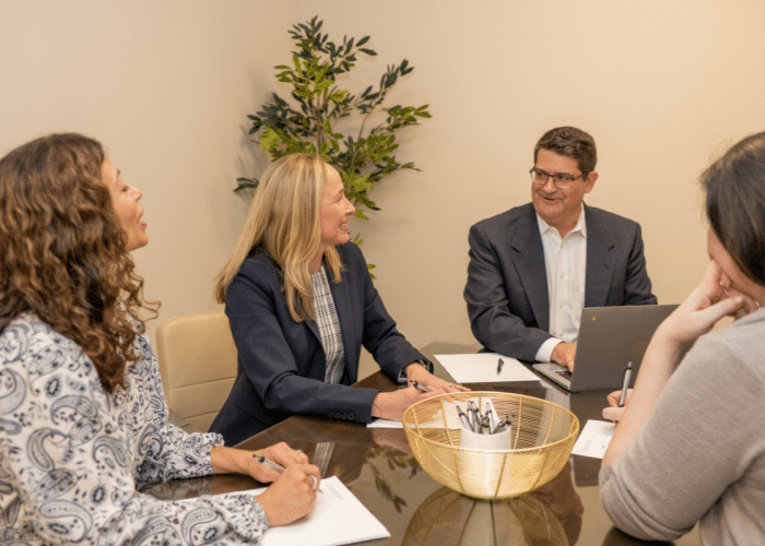 attorneys sitting around a table nd reviewing estate planning and financial documents.